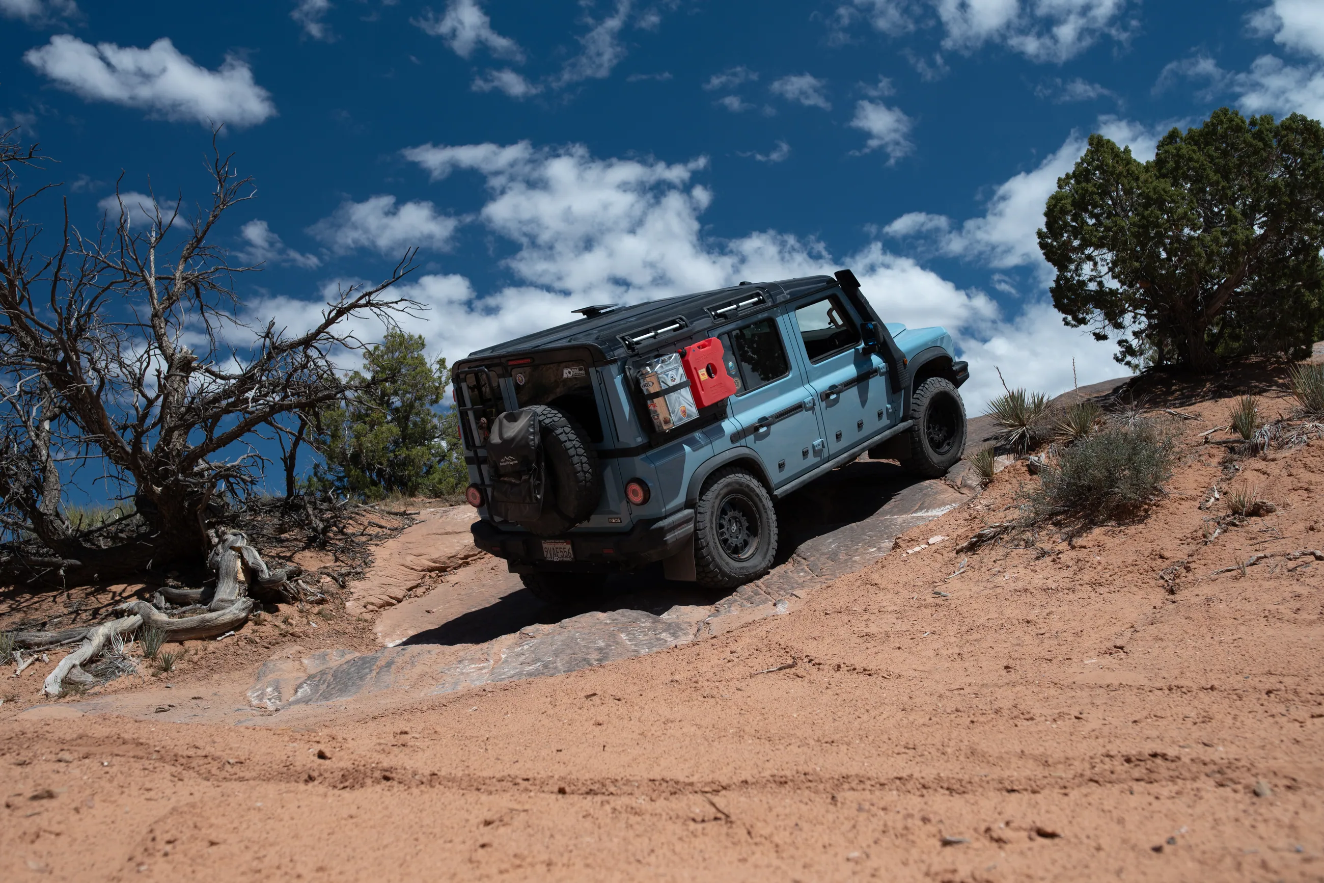 A Grenadier climbing a red sand slope under a blue sky with clouds