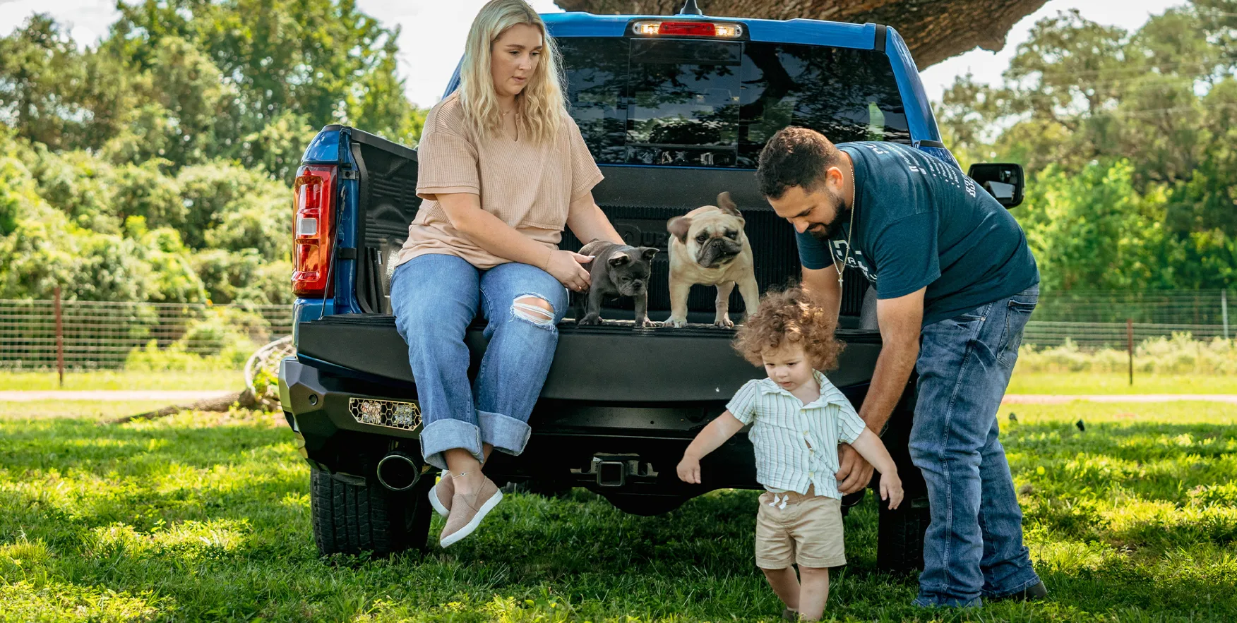 A family and their dogs at the tailgate of a truck at Oak Creek Ranch
