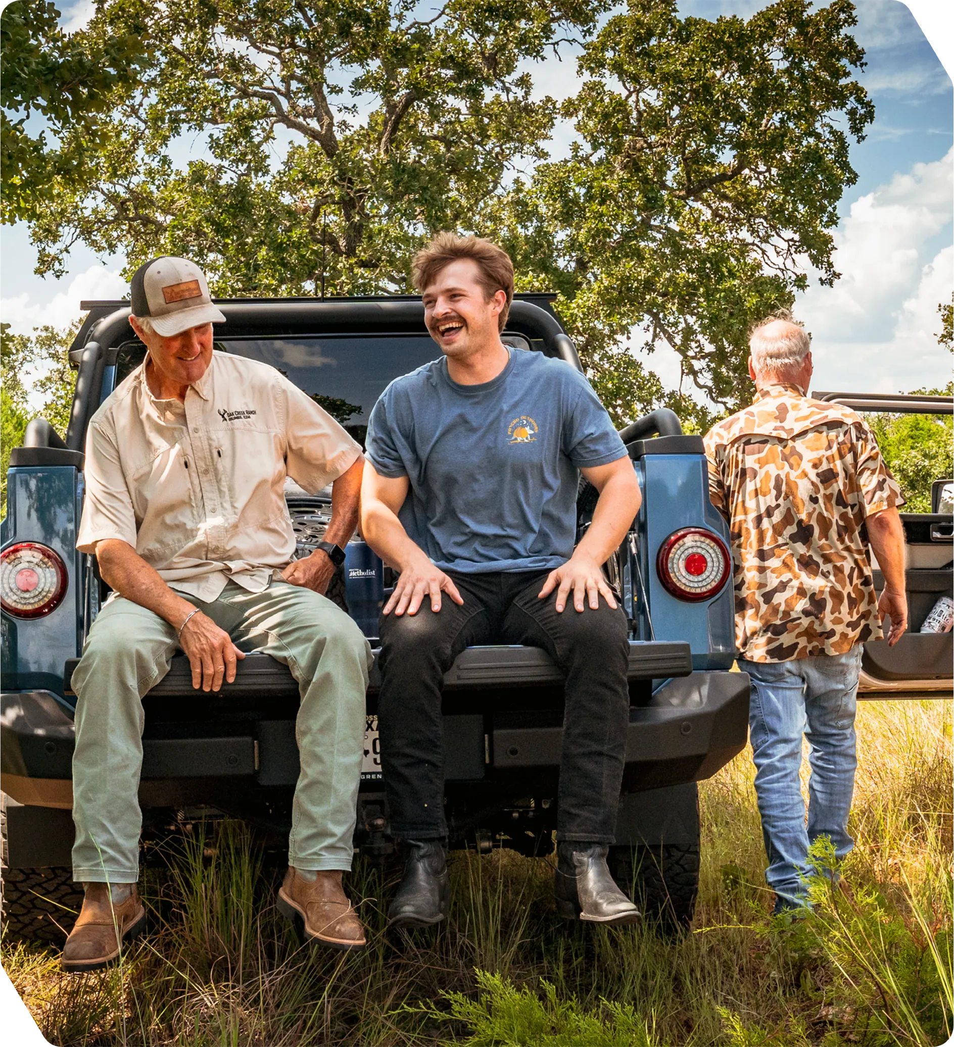 Three men sitting on the back of a Jeep at Oak Creek Ranch