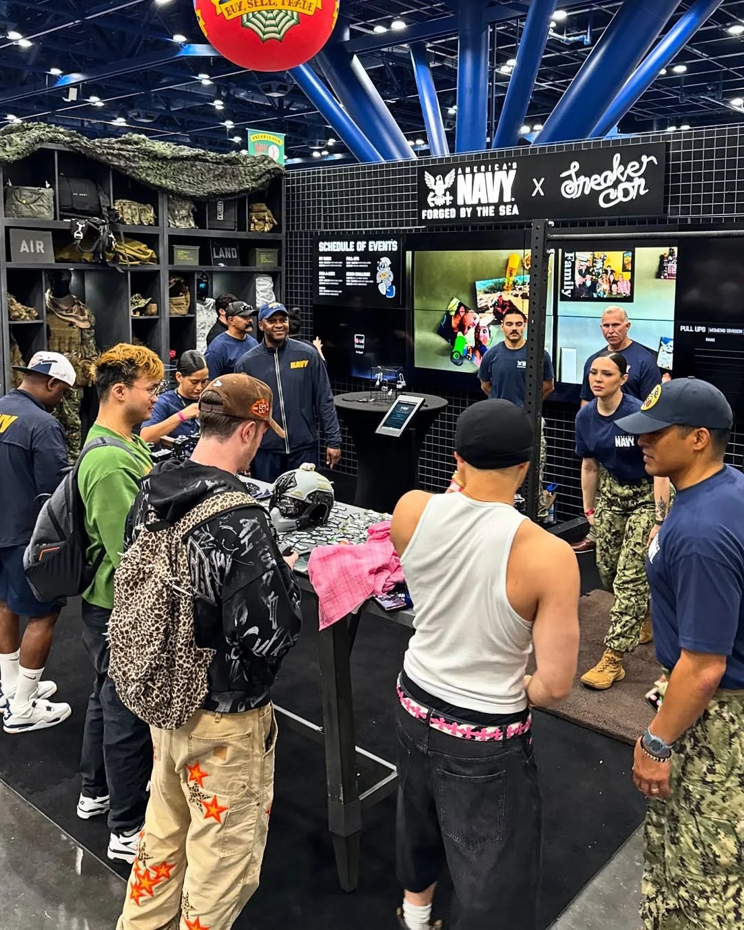 Visitors at the America’s Navy × Sneaker Con booth talking with sailors